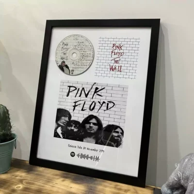 تابلوی قاب شده آلبوم The Wall از گروه پینک فلوید شامل کاور سیاه و سفید، CD آلبوم و بارکد Spotify