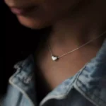 گردنبند نقره با آویز قلب روی گردن دختر با ژاکت جین