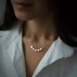 گردنبند نقره با مروارید پرورشی روی گردن دختر با پیراهن سفید، سبک کلاسیک و زنانه