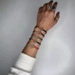 نمای نزدیک از دستبند نقره راکت تنیس روی دست خانم با تنوع رنگی