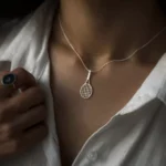 گردنبند نقره راکت تنیس روی گردن زن با پیراهن سفید و نور طبیعی